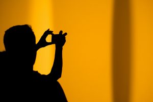 photo au smartphone-Personne en silhouette sur fond orangé-marron photographiant au smartphone